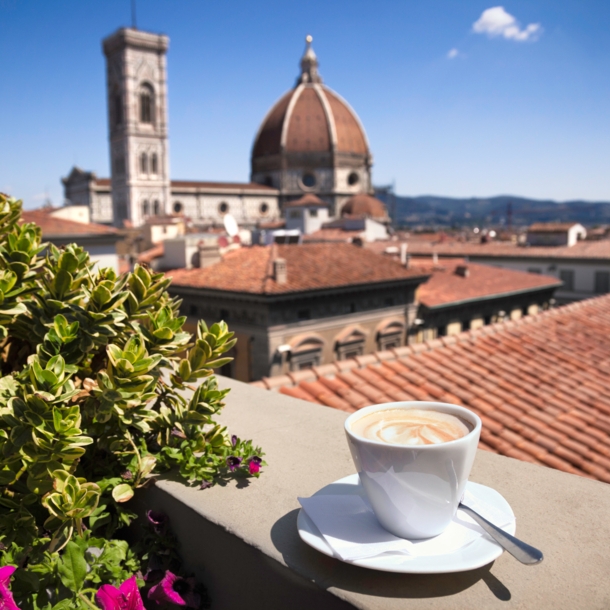 Stadtpanorama von Florenz mit Dom, im Vordergrund eine weiße Cappuccinotasse auf einer Mauer.