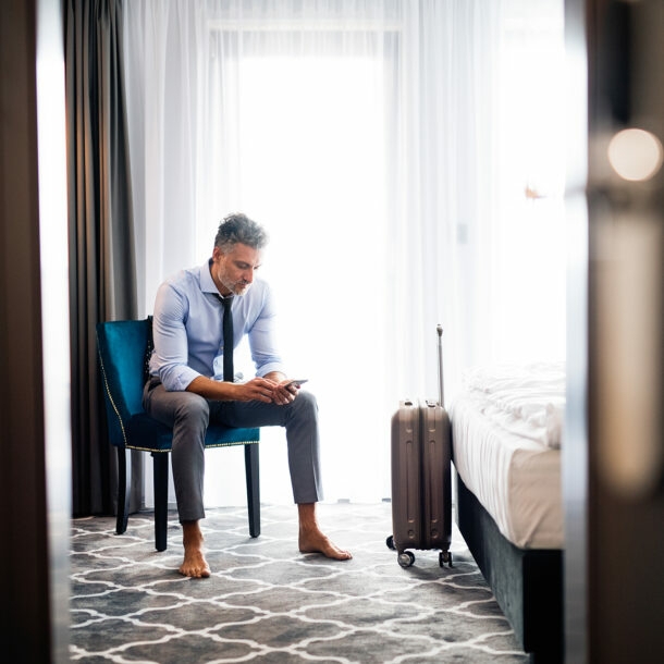 GEschäftsmann im Hotelzimmer schaut auf sein Smartphone