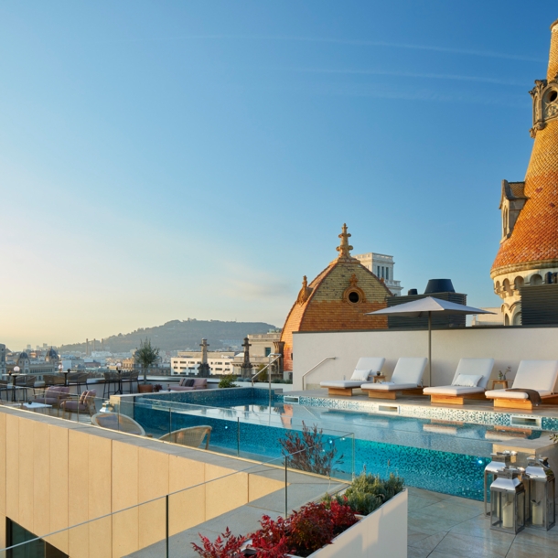 Hotelpool mit Sonnenliegen auf einer modernen Dachterrasse im Stadtzentrum.