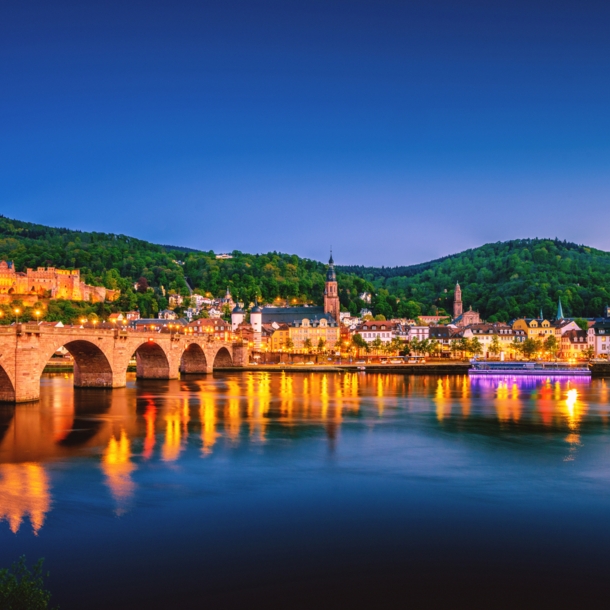 Blick auf die Heidelberger Skyline bei Nacht mit dem Neckar und der Alten Brücke im Vordergrund.