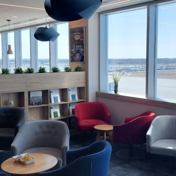 Flughafen-Lounge mit Sitzgruppen und Blick aufs Rollfeld.