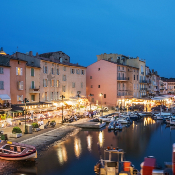 Beleuchtete Restaurants am Hafen von Saint Tropez am Abend.