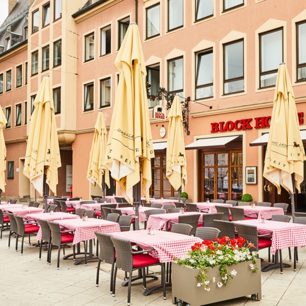 Block House Restaurant mit Außengastronomie auf einem Platz in einer Altstadt.