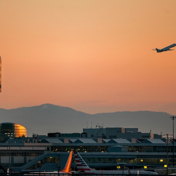 Tower des Vancouver Airports bei Sonnenuntergang und ein startendes Flugzeug.