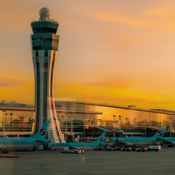 lughafenterminal mit Tower und geparkten Flugzeugen bei Sonnenuntergang.