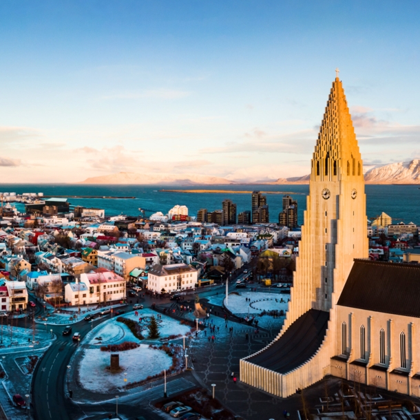 Skyline von Reykjavik mit Pfarrkirche vor Meerespanorama mit schneebedeckten Bergen.