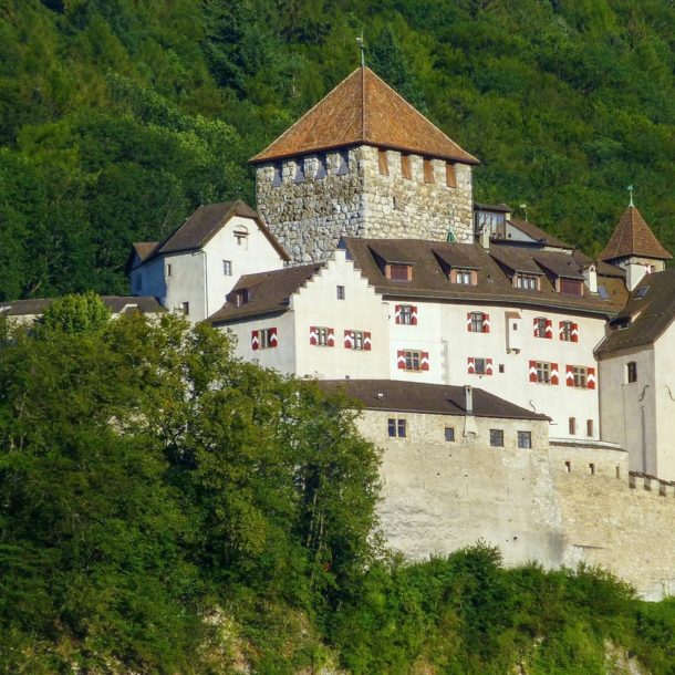 Mittelalterliche Burganlage auf einer Felsterrasse an einem bewaldeten Hügel.