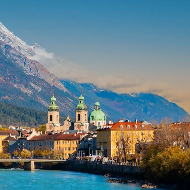 Skyline der Innsbrucker Altstadt am Fluss vor Bergpanorama.