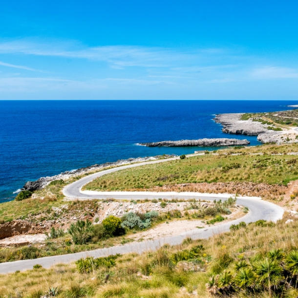 Kurvige Küstenstraße in mediterraner Landschaft.