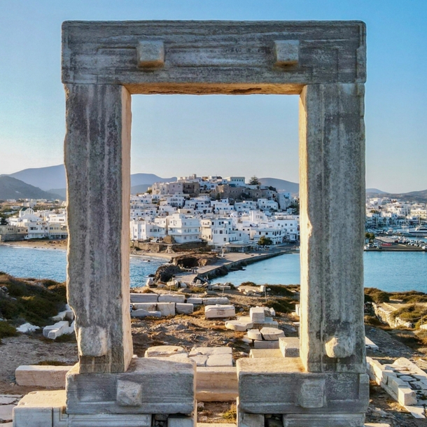 Blick auf die Stadt Naxos auf einer Insel durch ein Steintor in einer antiken Ruinenstätte auf einem Hügel.