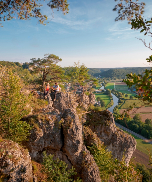 Zwei Wanderer sitzen auf einem Felsen hoch über der Altmühl