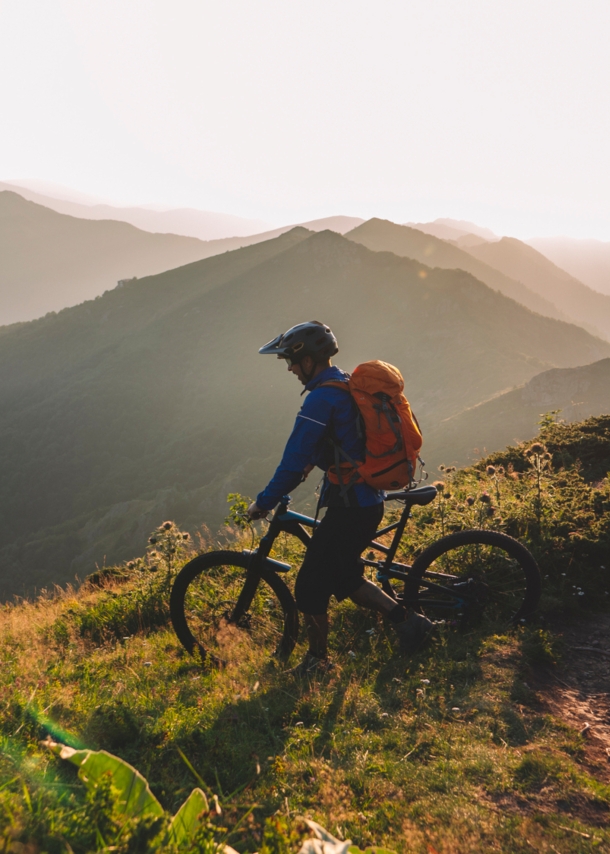 Mountainbiker steht mit seinem Rad auf einem Berg und schaut ins Tal