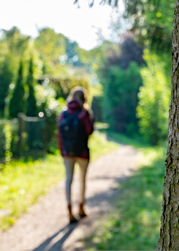 Eine Frau geht einen geschotterten schmalen Wanderweg entlang