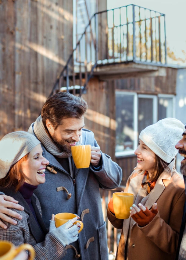 Freunde stehen im Winter vor eine Holzhütte und lachen und reden miteinander