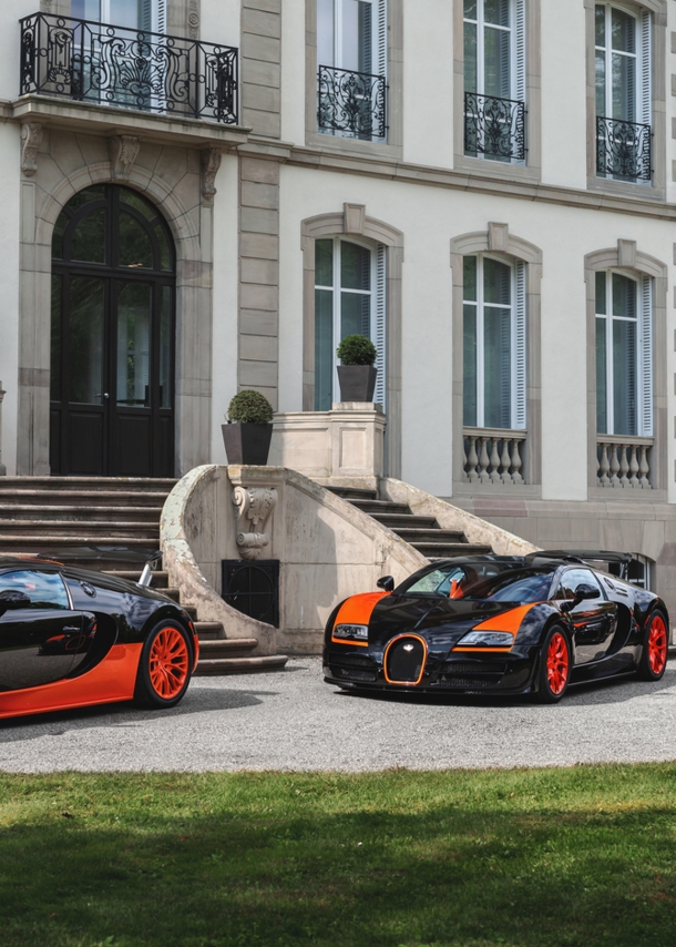 Drei Modelle von Bugatti vor einem Schloss