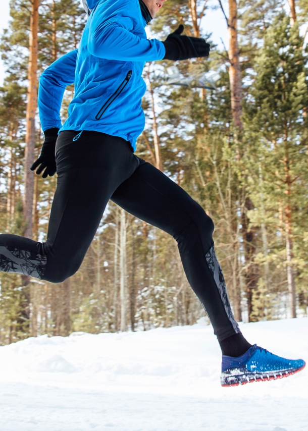 Ein Mann joggt im verschneiten Wald.