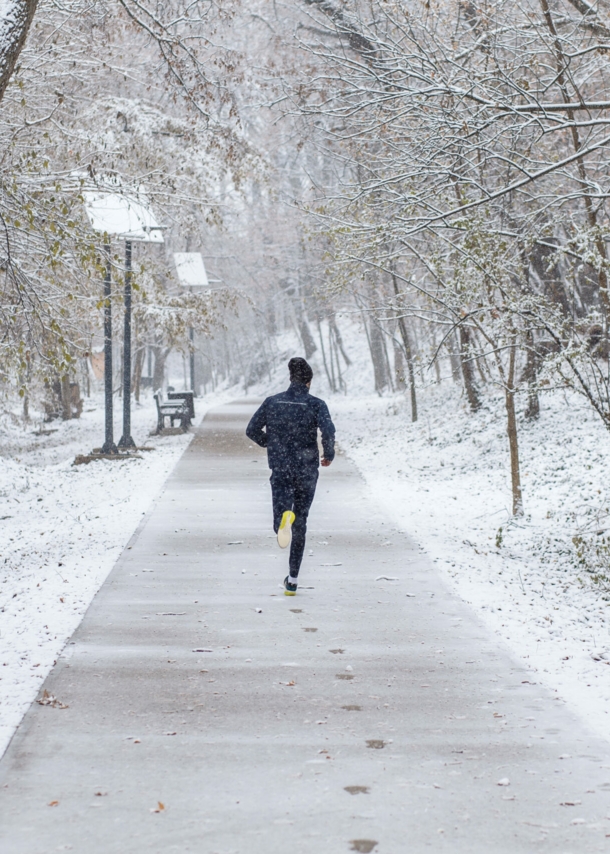 Mann von hinten fotografiert beim Joggen durch eine Winterlandschaft