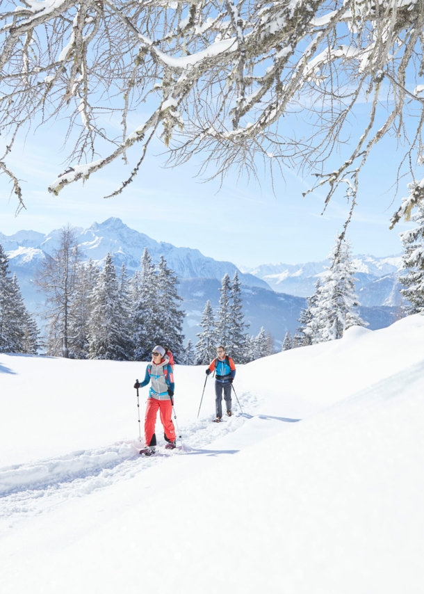 Zwei Wandernde mit Stöcken in einer verschneiten Berglandschaft