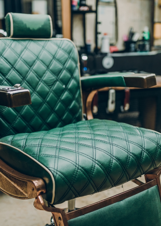 Ein Vintage-Barbersessel mit grünem Lederbezug in einem Barbershop