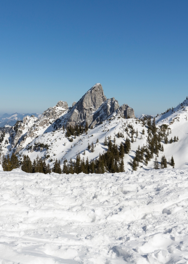 Blick auf die teilweise verschneiten Gipfel des Mangfallgebirges bei blauem Himmel