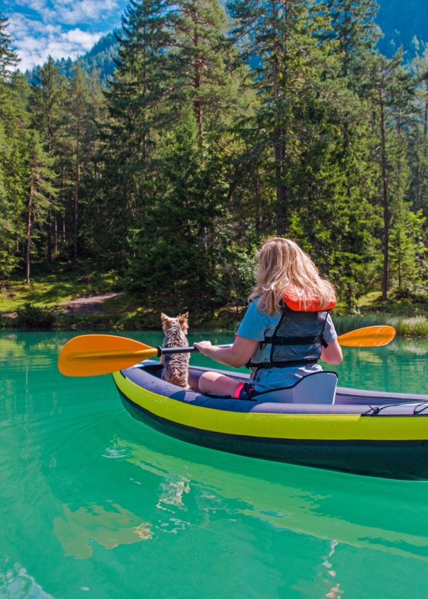 Eine Frau mit einem Hund im Kanu auf einem türkisfarbenen Fluss