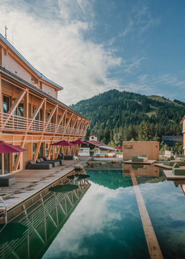 Ein Luxushotelanlage aus Holz mit Außenpool und Blick auf die Berge