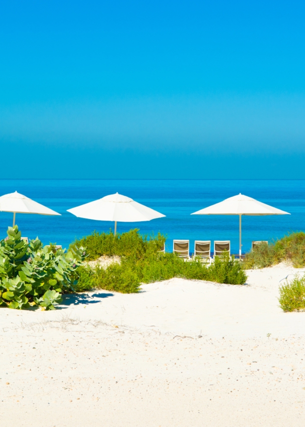 Sandstrand und blaues Meer mit Sonnenliegen und Sonnenschirmen