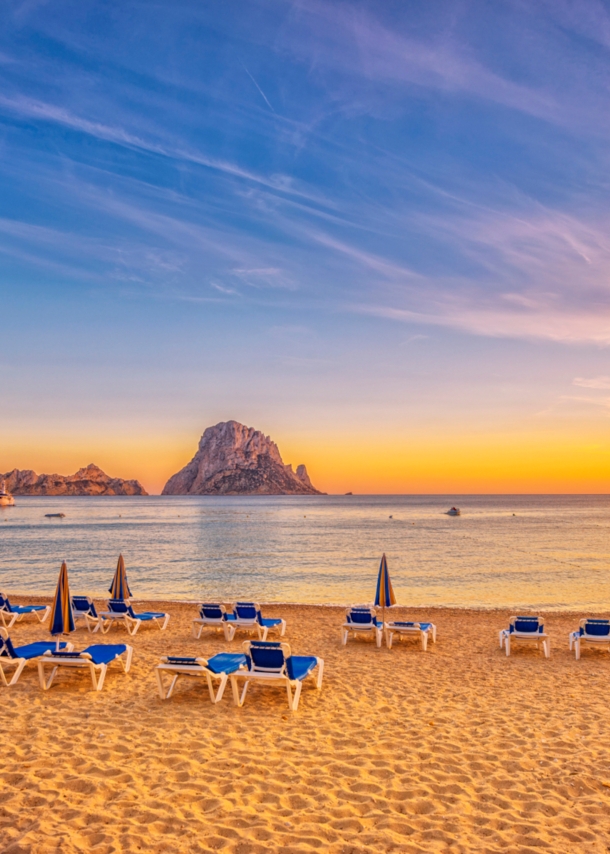 Ein Sandstrand mit Liegen bei Sonnenuntergang