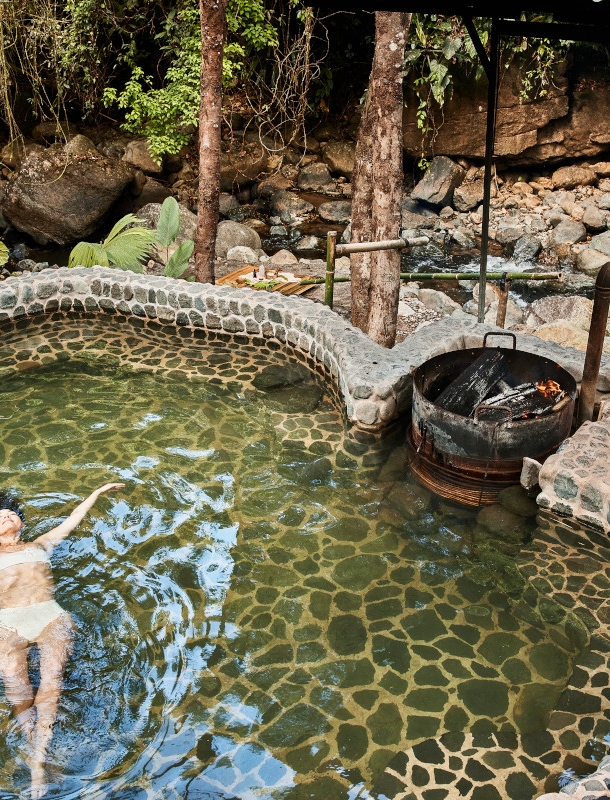 Eine Frau im weißen Bikini lässt sich in einem Teich treiben