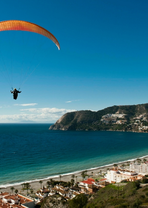 Ein Paraglider schwebt über einer Küstenstadt