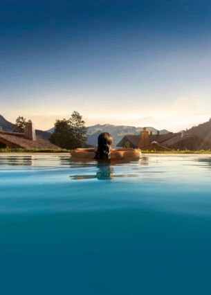 Rückansicht einer Person in einem Pool, im Hintergrund Berge