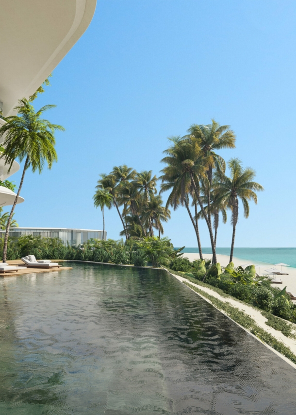 Poolbereich eines luxuriösen Hotels, mit Palmen gesäumt und Strandabschnitt im Hintergrund