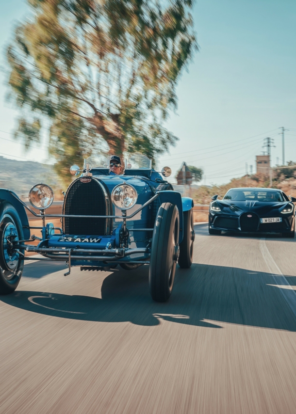 Ein Oldtimer und ein moderner Sportwagen auf einer Straße