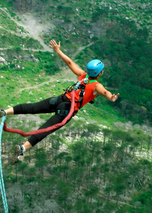 Eine Frau springt von einer Klippe am Bungeeseil in den Abgrund.