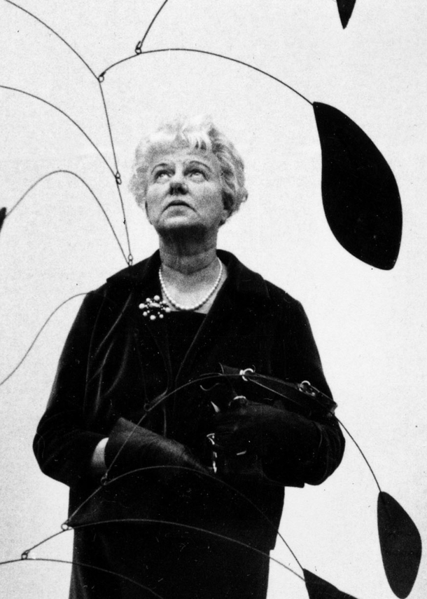 Porträt von Peggy Guggenheim, die in einer Kunstausstellung ein Mobile betrachtet