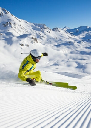 Ein Skifahrer im gelben Skianzug in Kurvenlage auf einer Piste