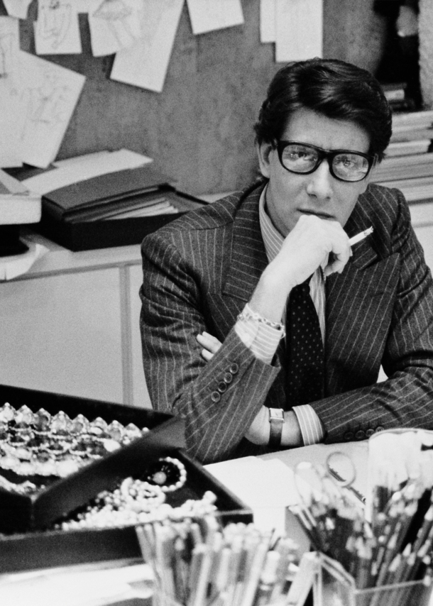 Schwarz-weiß-Aufnahme von Yves Saint Laurent an einem Schreibtisch in Paris 1986.