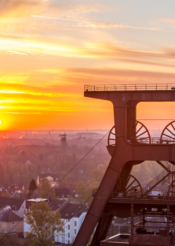 Blick auf Doppelbock-Fördergerüst vom Dach der Kohlenwäsche des UNESCO-Welterbes Zollverein beim Sonnenaufgang