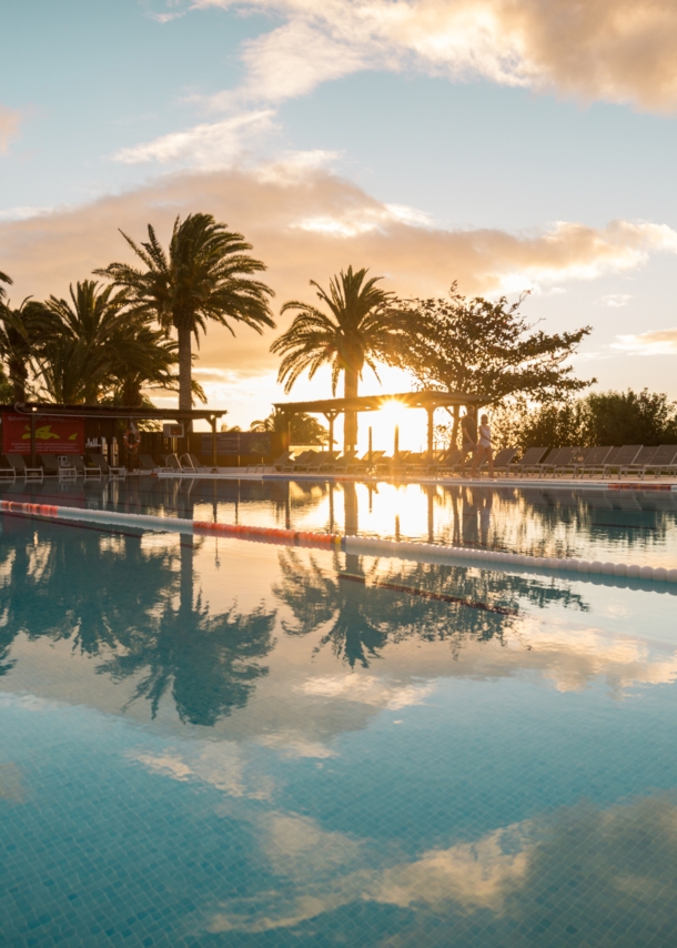 Ein großer Außenpool in einer Hotelanlage am Meer bei Sonnenuntergang