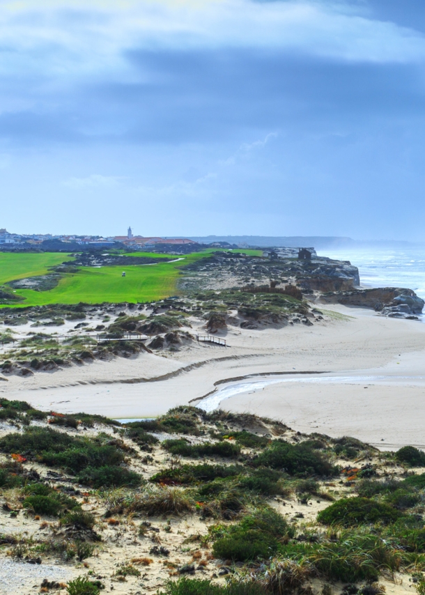 Ein hügeliger Golfplatz neben einem Sandstrand an einem wilden Küstenabschnitt