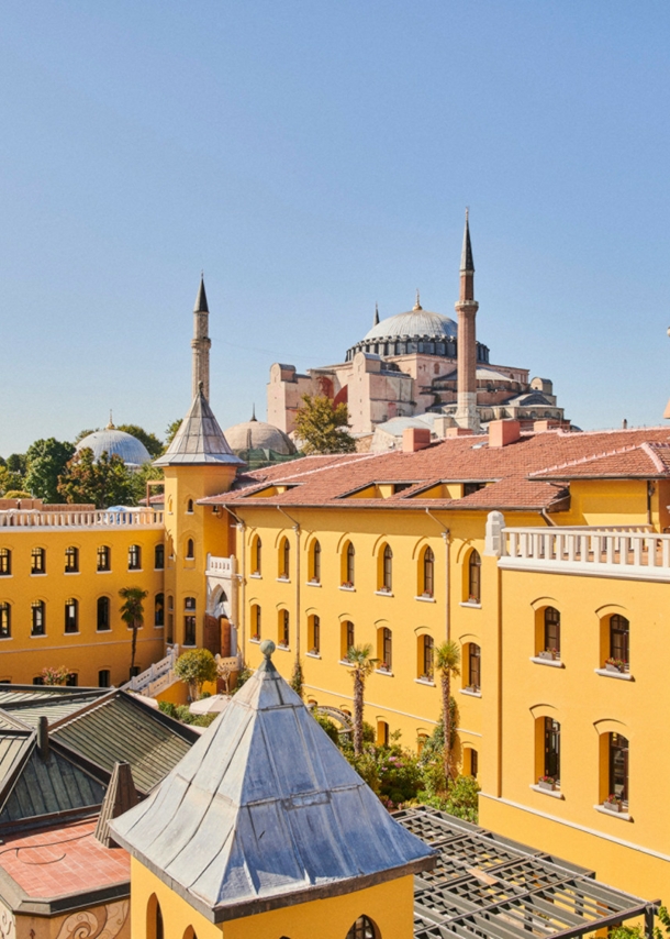 Ein gelbes, neoklassizistisches Gebäude mit Innenhof und einer Moschee im Hintergrund