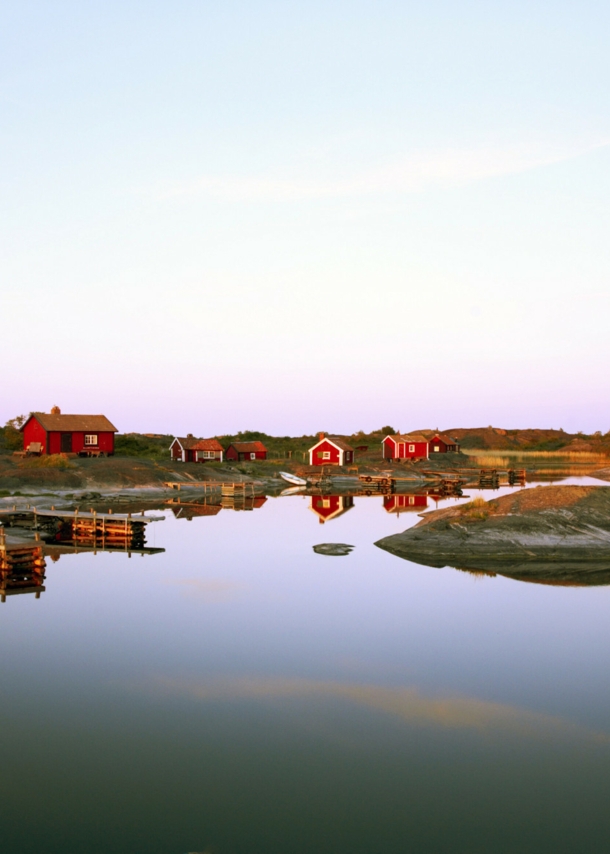 Blick auf rote Holzhäuser auf einer Insel in Schweden