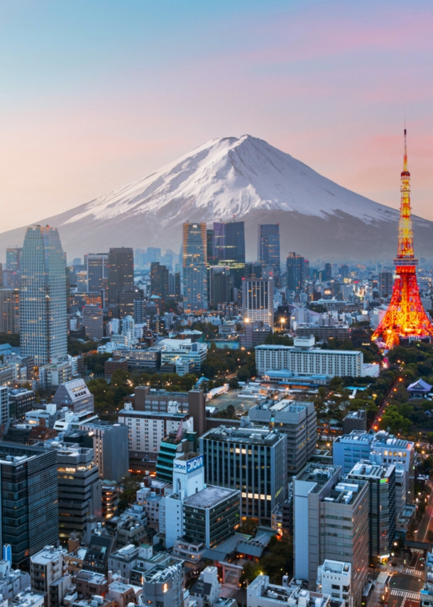 Skyline von Tokio mit beleuchtetem Fernsehturm vor schneebedecktem Fuji in der Abenddämmerung