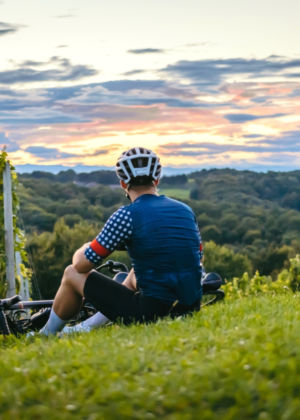 Rückenansicht zweier Personen in Fahrradkleidung, die auf einem Weinberg sitzen