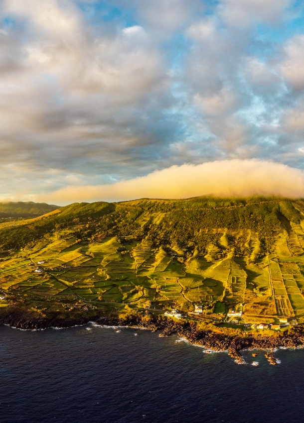 Luftaufnahme der Vulkaninsel Graciosa mit sanften, grünen Hügellandschaften bei Sonnenuntergang.