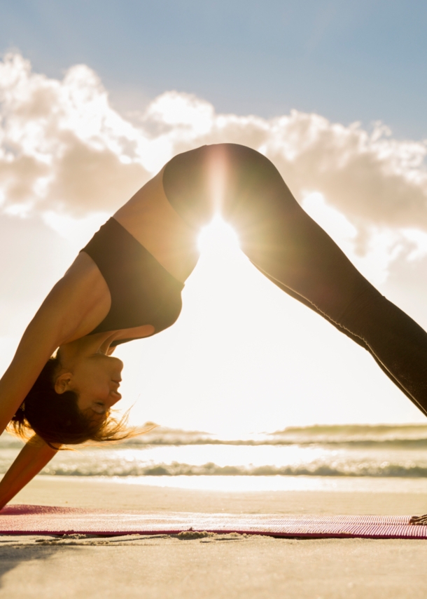 Eine Frau in einer Yoga-Pose am Strand. 