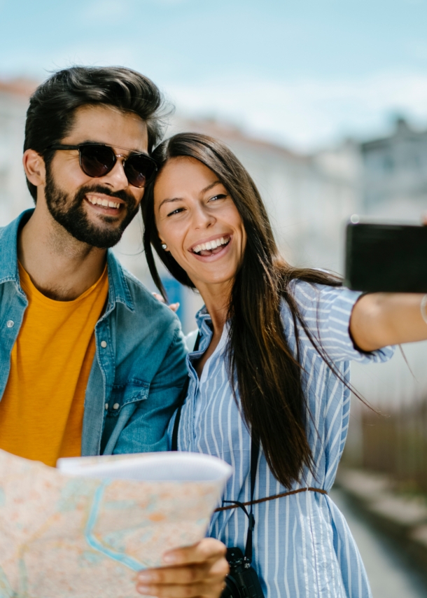 Ein fröhliches Paar mit Straßenplan beim Selfie fotografieren in urbaner Umgebung.