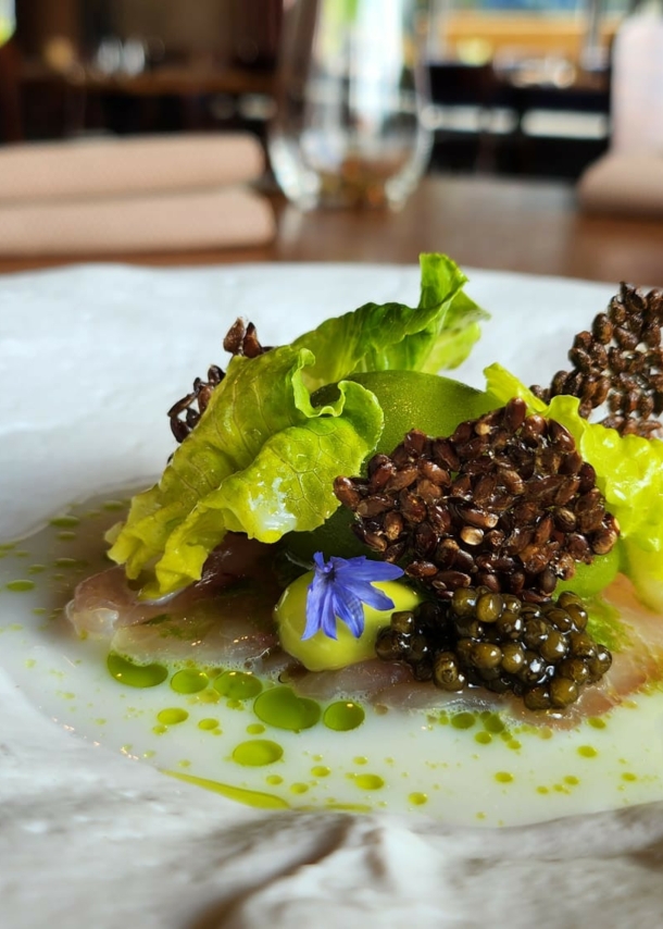 Ein weißer, unebener Teller, in dessen Mitte ein Gourmet-Gericht im Restaurant ZweiSinn Meiers angerichtet ist.