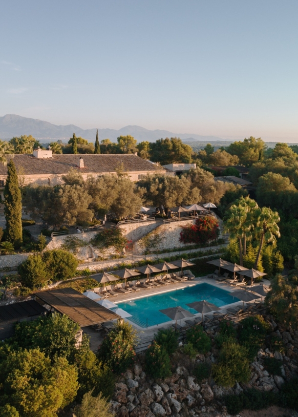 Luftaufnahme einer Finca mit Pool inmitten einer bewaldeten Hügellandschaft.