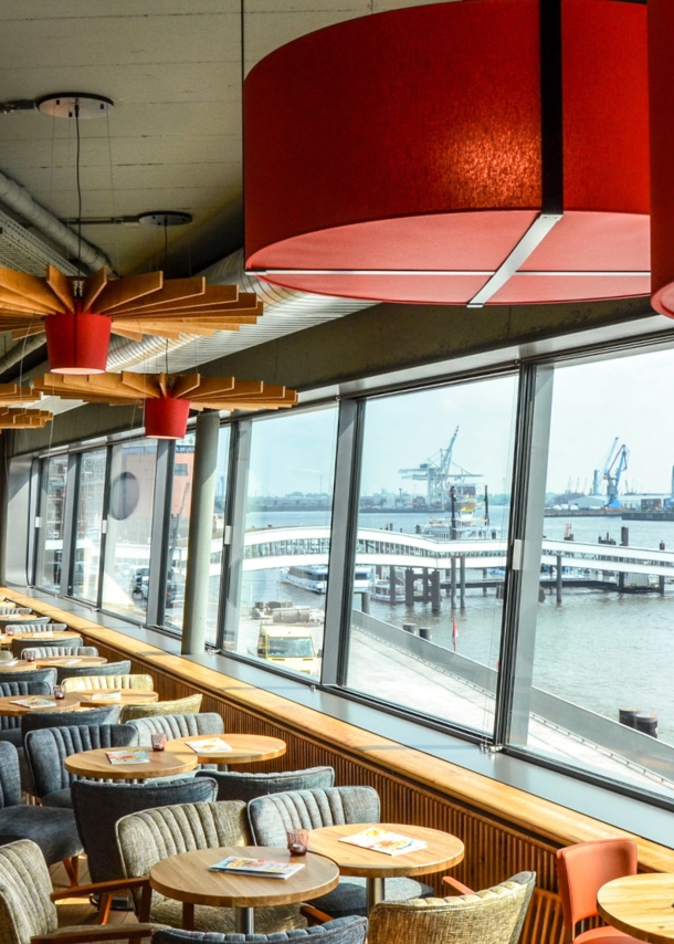 Modernes Bistro mit Blick auf den Hamburger Hafen durch Panoramafenster.